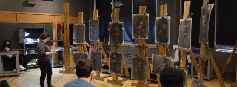 Students viewing art work displayed on easles