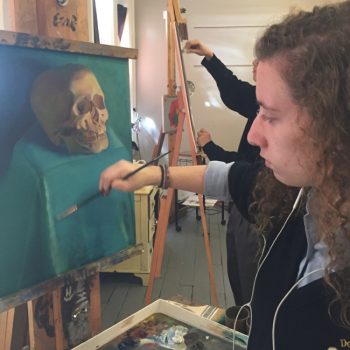 Women at an easle painting a skull